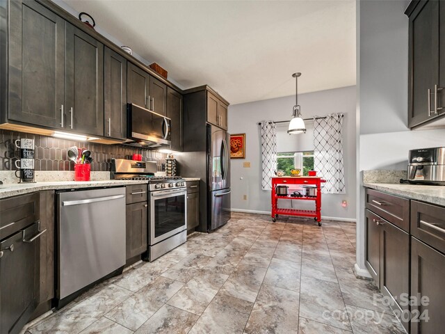 kitchen with dark brown cabinets, pendant lighting, light stone counters, tasteful backsplash, and appliances with stainless steel finishes