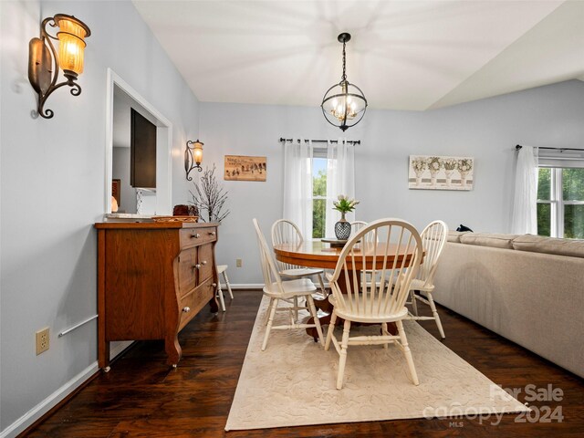 dining space with lofted ceiling, dark hardwood / wood-style floors, a chandelier, and a healthy amount of sunlight