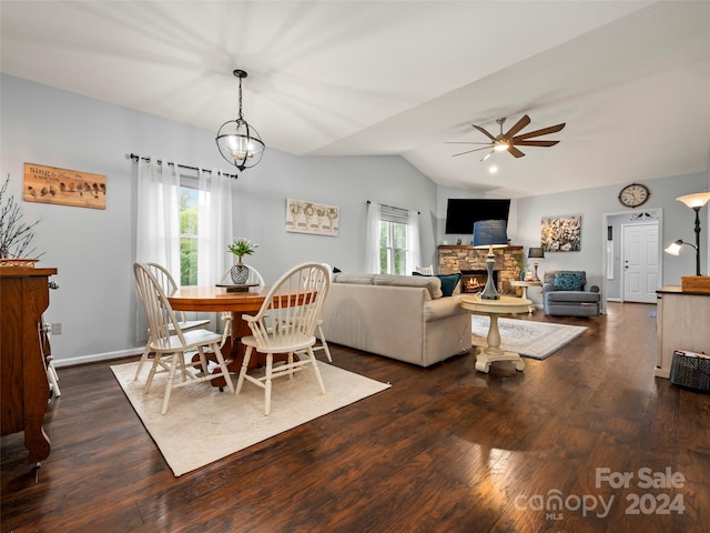 dining area featuring ceiling fan with notable chandelier, a wealth of natural light, vaulted ceiling, and a fireplace