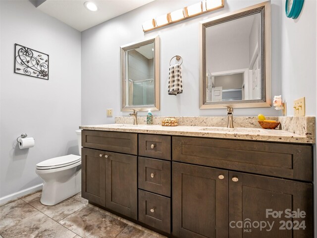 bathroom featuring a shower with shower door, vanity, and toilet