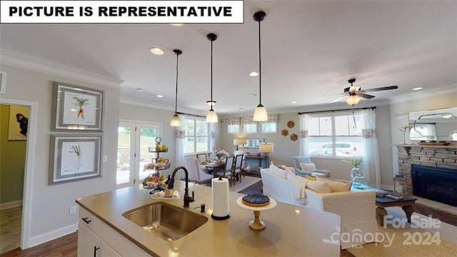 kitchen with crown molding, sink, ceiling fan, a fireplace, and decorative light fixtures