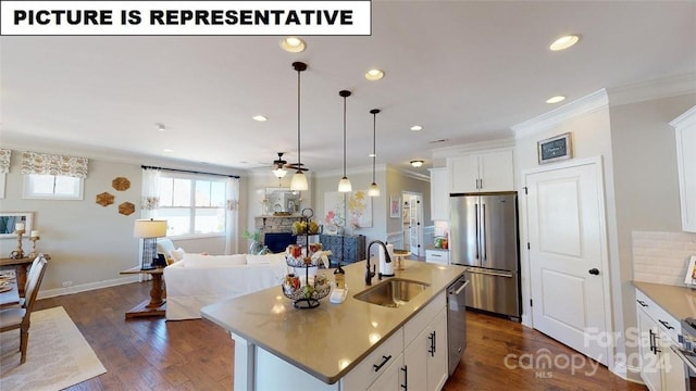 kitchen with pendant lighting, white cabinets, sink, an island with sink, and appliances with stainless steel finishes