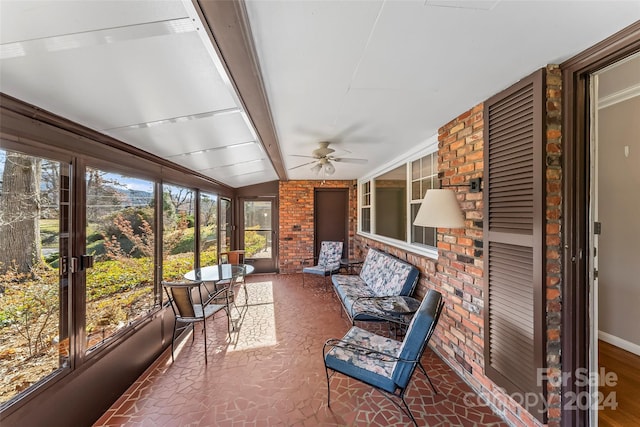 unfurnished sunroom with ceiling fan and lofted ceiling with beams