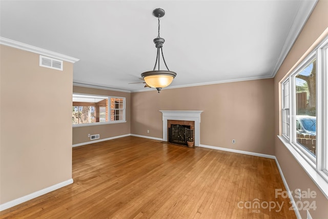 unfurnished living room with light wood-type flooring, a wealth of natural light, and ornamental molding