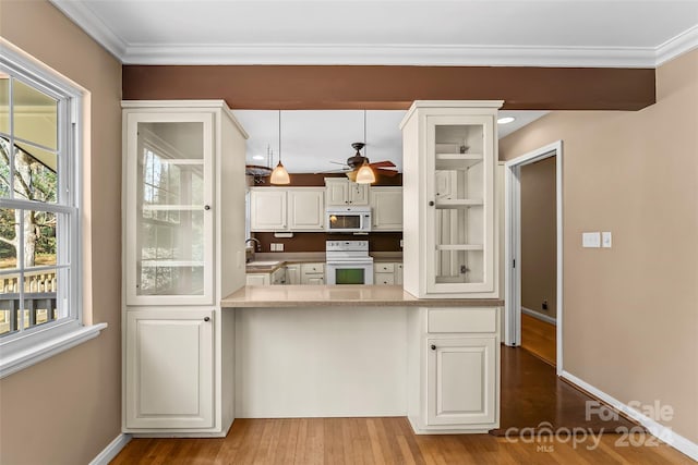 kitchen with white appliances, sink, light wood-type flooring, decorative light fixtures, and white cabinetry