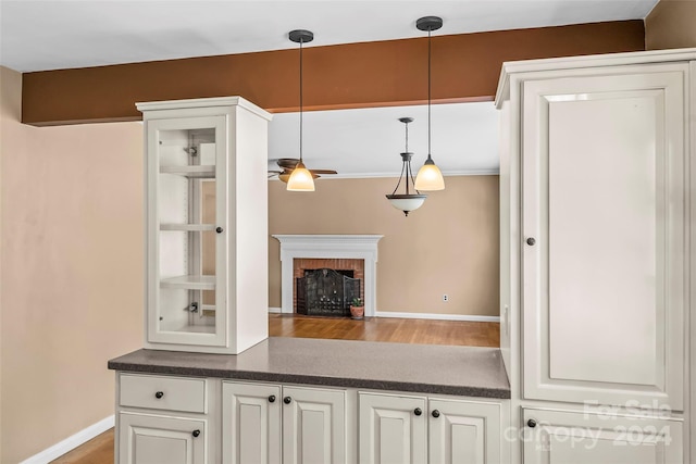 kitchen featuring a fireplace, pendant lighting, white cabinetry, and ceiling fan