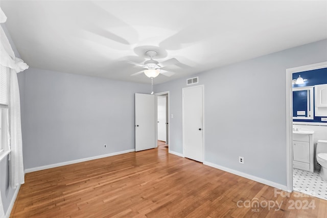 unfurnished bedroom with ensuite bathroom, ceiling fan, and light hardwood / wood-style floors