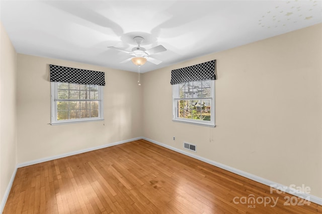 unfurnished room with hardwood / wood-style floors, ceiling fan, and a healthy amount of sunlight