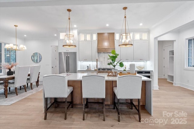 kitchen with hanging light fixtures, appliances with stainless steel finishes, and custom range hood