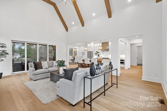 living room with beam ceiling, a chandelier, high vaulted ceiling, and light hardwood / wood-style flooring