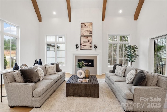 living room featuring a towering ceiling, a wealth of natural light, and beamed ceiling