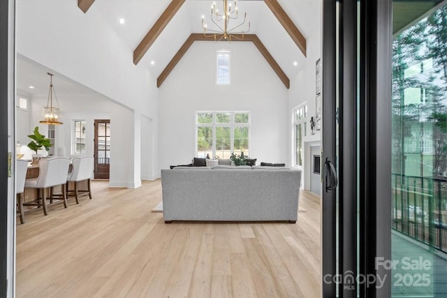 living room featuring an inviting chandelier, high vaulted ceiling, light hardwood / wood-style flooring, and beamed ceiling