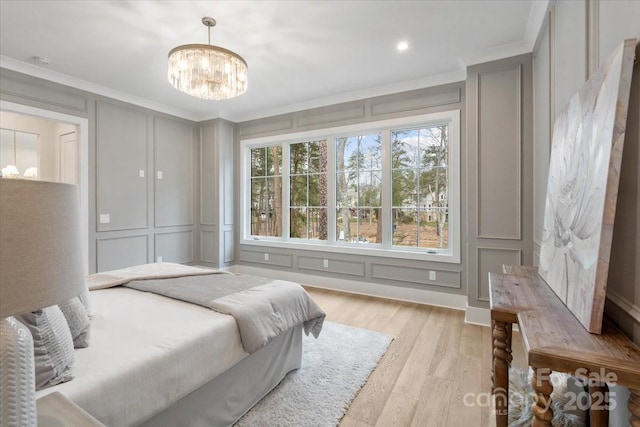 bedroom with crown molding, a chandelier, and light hardwood / wood-style floors