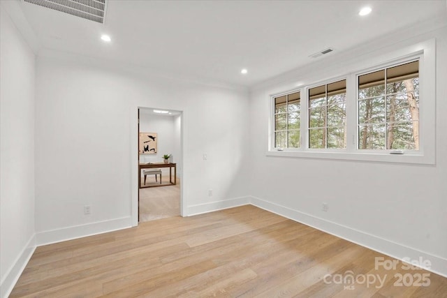 empty room featuring crown molding, a wealth of natural light, and light hardwood / wood-style floors