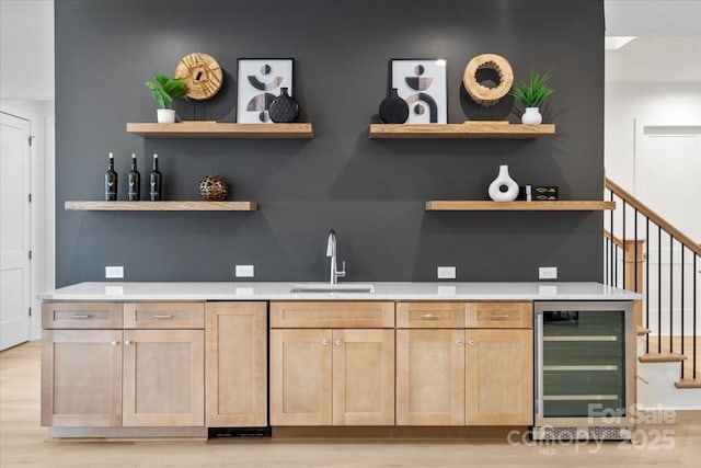 bar with wine cooler, sink, light hardwood / wood-style flooring, and light brown cabinets