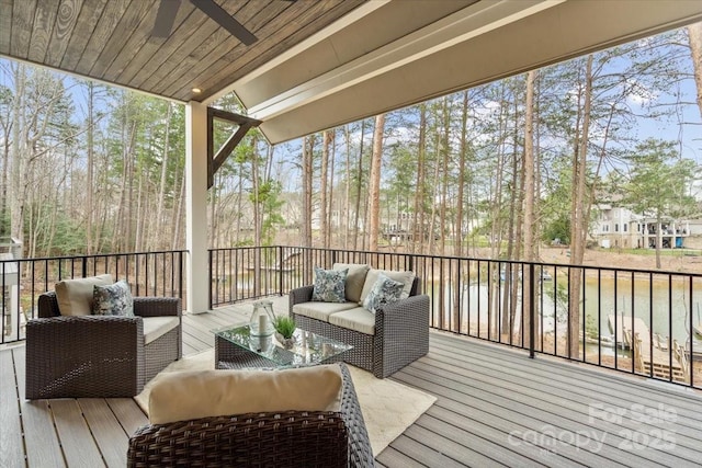 wooden terrace with a water view, ceiling fan, and outdoor lounge area