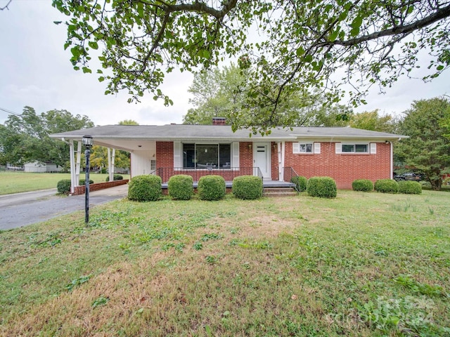 ranch-style house featuring a porch, a front lawn, and a carport