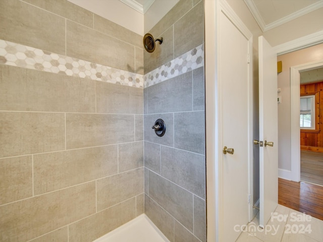 bathroom with wood-type flooring, crown molding, and tiled shower