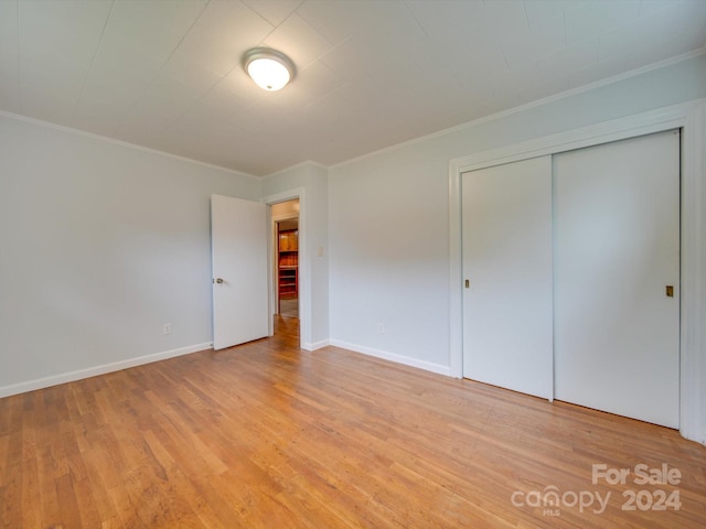 unfurnished bedroom featuring a closet, ornamental molding, and light hardwood / wood-style flooring