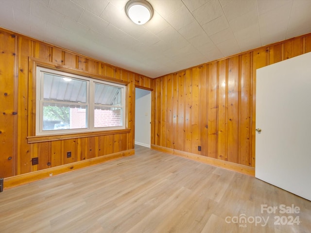 spare room featuring light hardwood / wood-style flooring and wood walls