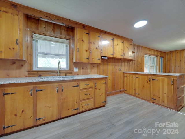 kitchen featuring light hardwood / wood-style flooring, wooden walls, kitchen peninsula, and sink