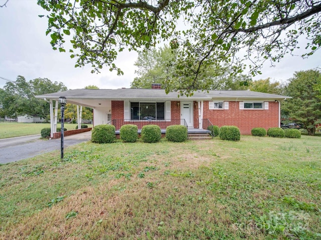 ranch-style home with a carport, covered porch, and a front yard