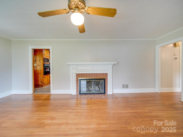 unfurnished living room featuring a brick fireplace, baseboards, crown molding, and light wood finished floors