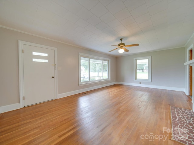 entrance foyer featuring ornamental molding, light wood-type flooring, a wealth of natural light, and baseboards