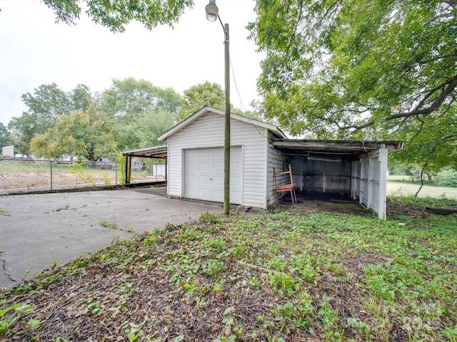 garage featuring driveway, a detached garage, and fence