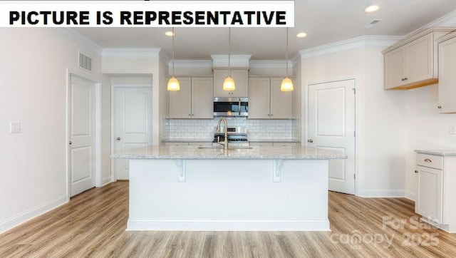 kitchen with light stone countertops, ornamental molding, stainless steel appliances, and a center island with sink