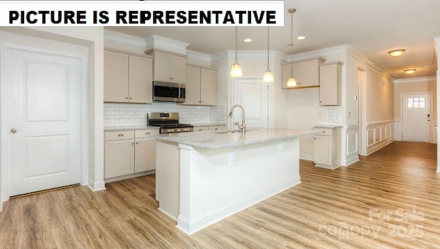 kitchen with sink, decorative light fixtures, an island with sink, stainless steel appliances, and light stone countertops