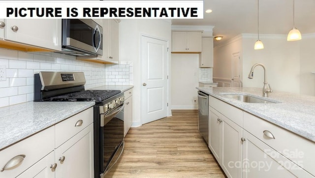 kitchen featuring white cabinetry, stainless steel appliances, sink, and hanging light fixtures