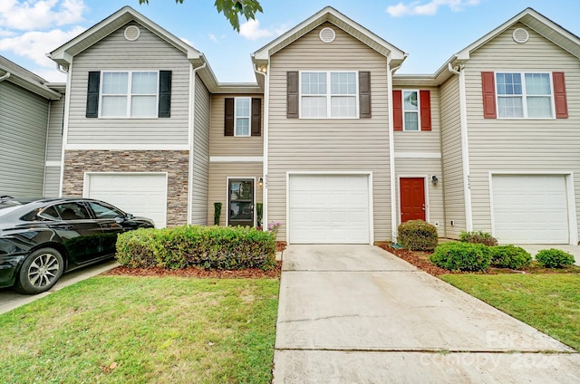 view of property featuring a garage and a front lawn