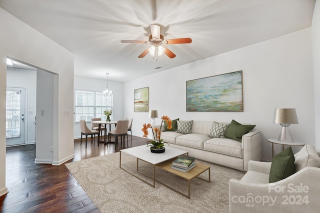 living room with ceiling fan with notable chandelier and dark hardwood / wood-style floors