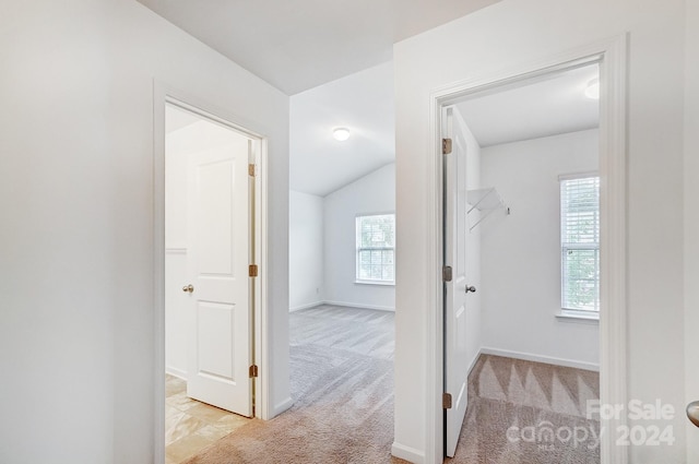 corridor featuring light colored carpet and lofted ceiling