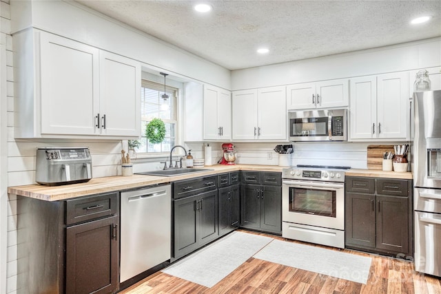 kitchen with sink, appliances with stainless steel finishes, a textured ceiling, and white cabinetry