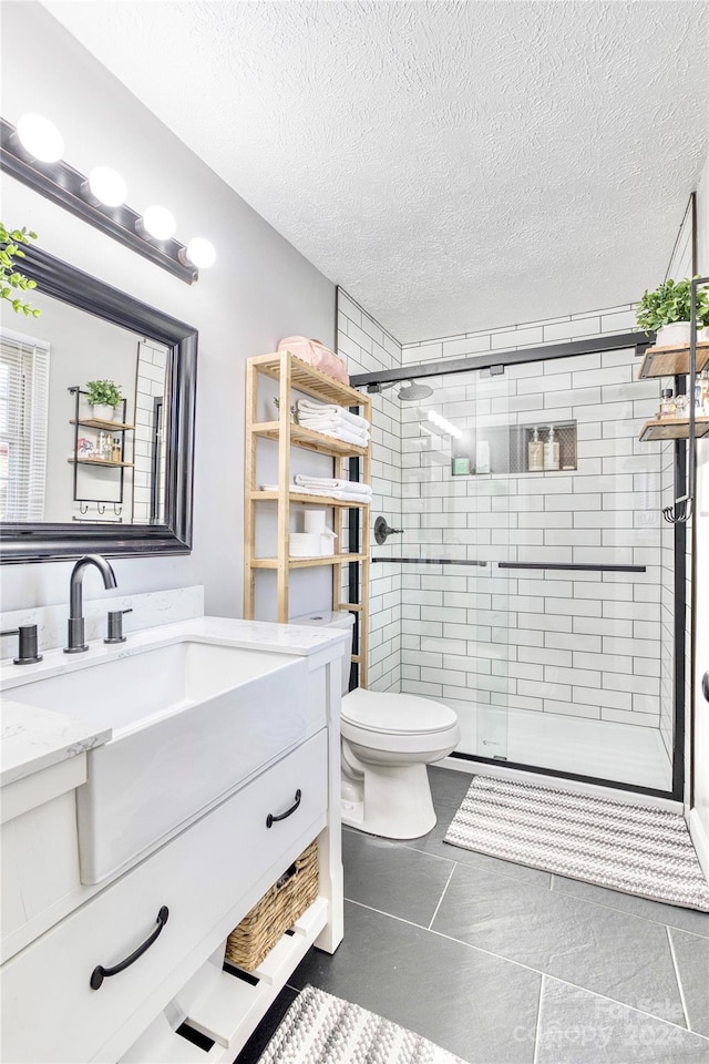 bathroom with vanity, a textured ceiling, toilet, and walk in shower