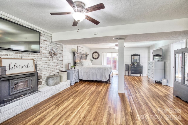 bedroom with a textured ceiling, decorative columns, hardwood / wood-style flooring, and ceiling fan