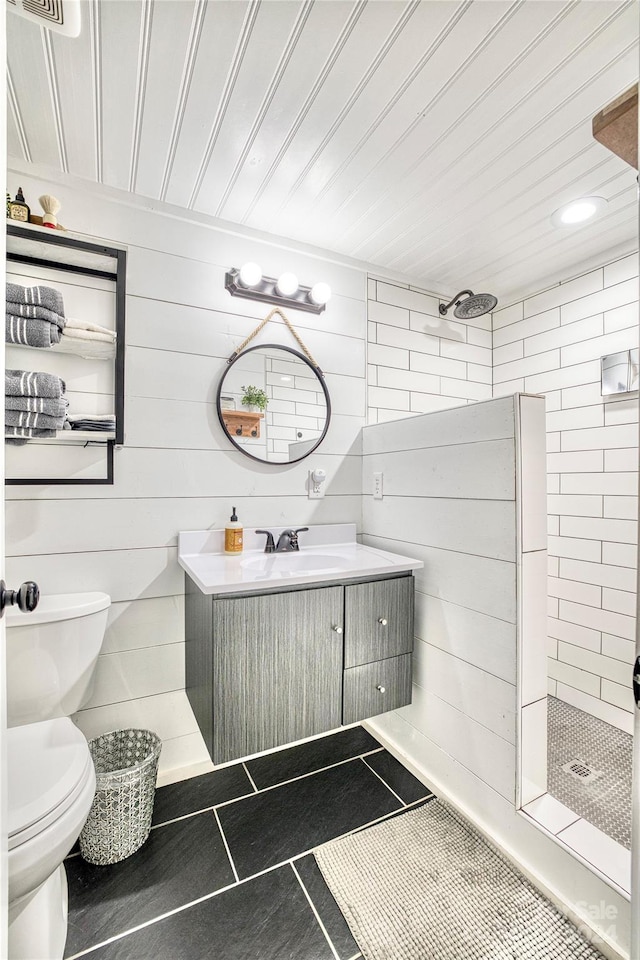 bathroom featuring vanity, tiled shower, toilet, and tile patterned flooring