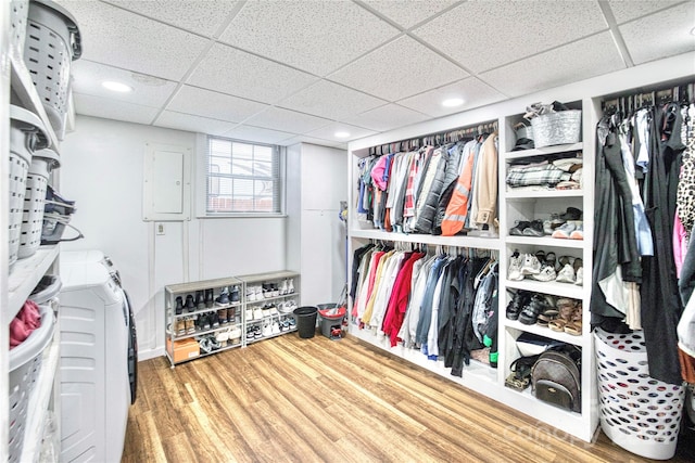 spacious closet with a drop ceiling, hardwood / wood-style floors, electric panel, and washing machine and clothes dryer