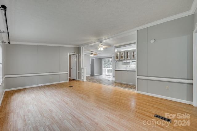 unfurnished living room with ceiling fan, a textured ceiling, crown molding, and light hardwood / wood-style floors