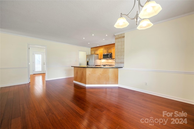 kitchen with ornamental molding, a textured ceiling, decorative light fixtures, appliances with stainless steel finishes, and dark hardwood / wood-style flooring