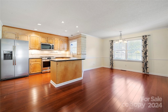 kitchen with a textured ceiling, dark wood-type flooring, kitchen peninsula, hanging light fixtures, and appliances with stainless steel finishes