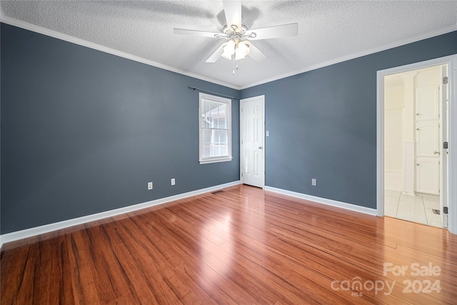 spare room featuring ceiling fan, a textured ceiling, ornamental molding, and wood-type flooring