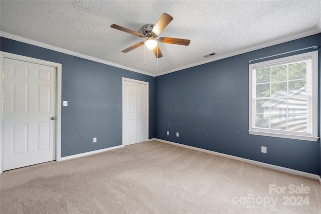 unfurnished bedroom featuring ceiling fan, carpet floors, ornamental molding, and a textured ceiling