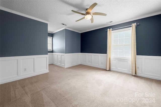 carpeted empty room featuring a textured ceiling, crown molding, and ceiling fan