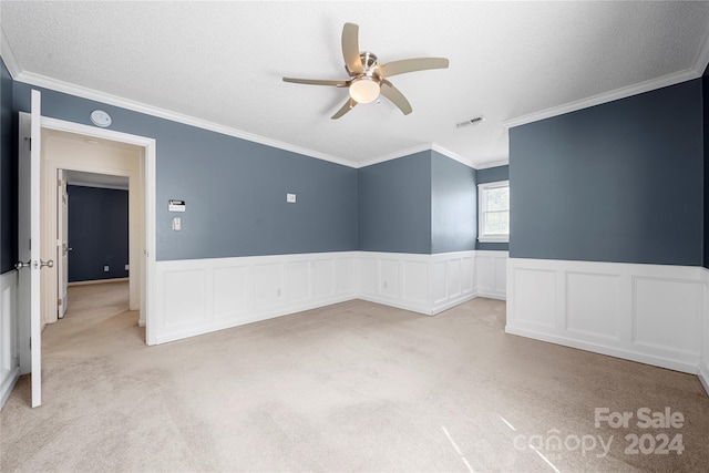 carpeted empty room with ceiling fan, a textured ceiling, and ornamental molding