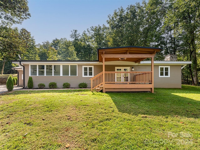 rear view of house with a deck and a yard