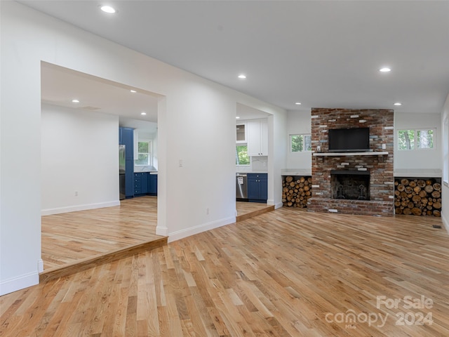 unfurnished living room with a fireplace, light hardwood / wood-style floors, and a wealth of natural light