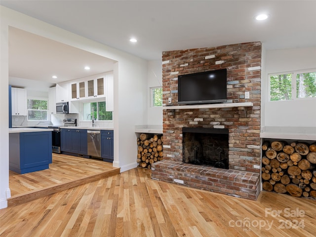 unfurnished living room featuring light hardwood / wood-style floors, a fireplace, and sink